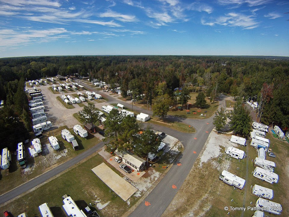 Aerial view of University Station RV Resort: rows of parked RVs along paved loops, surrounded by pine woods