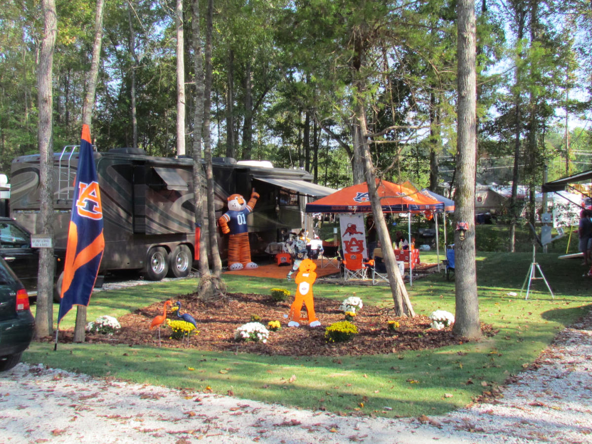 A motorhome on a shaded lot at University Station, set up for an Auburn game with a tent, flag and inflatable Aubie